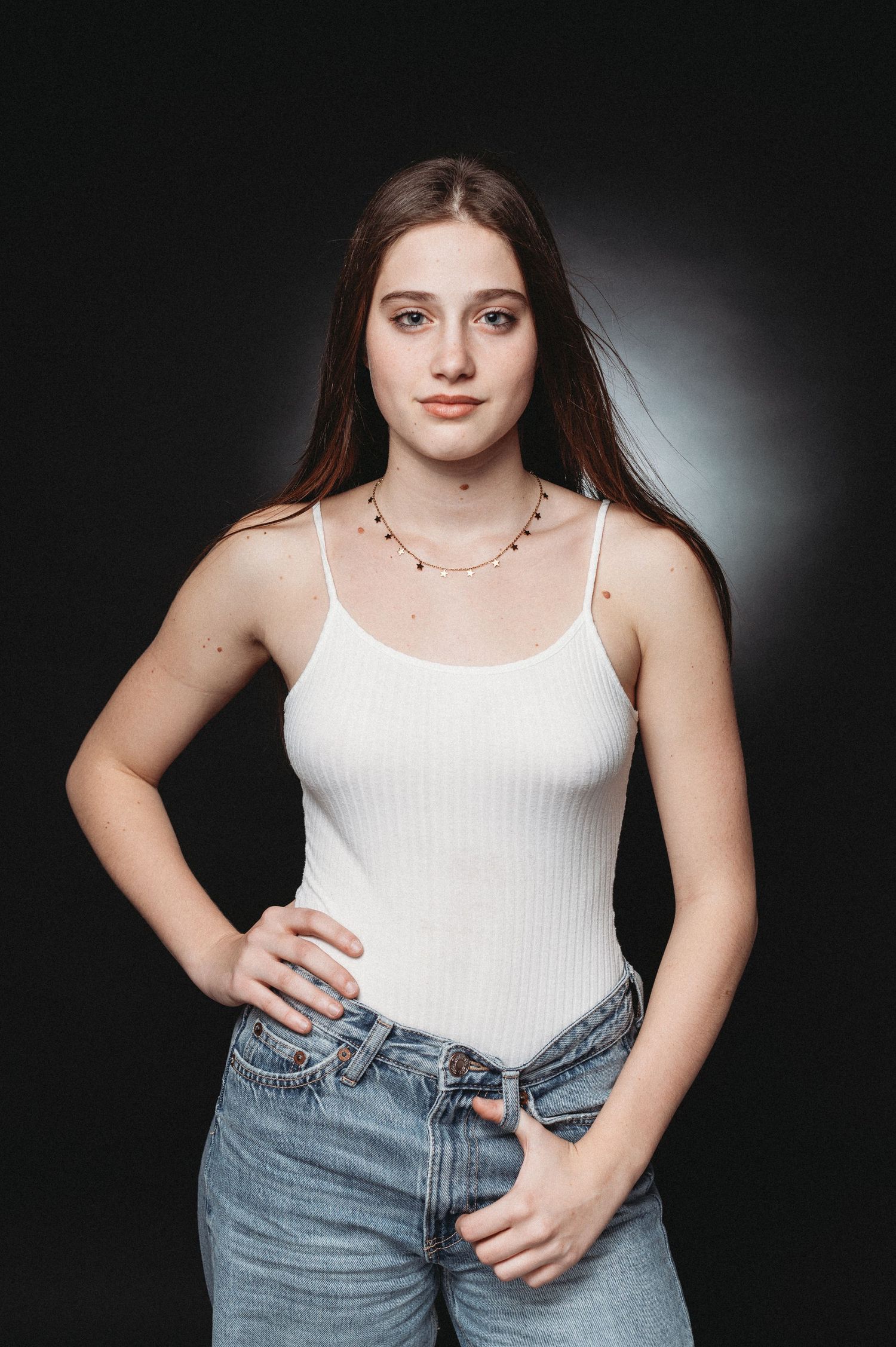 Studio portrait featuring casual style with white tank top and classic blue jeans.