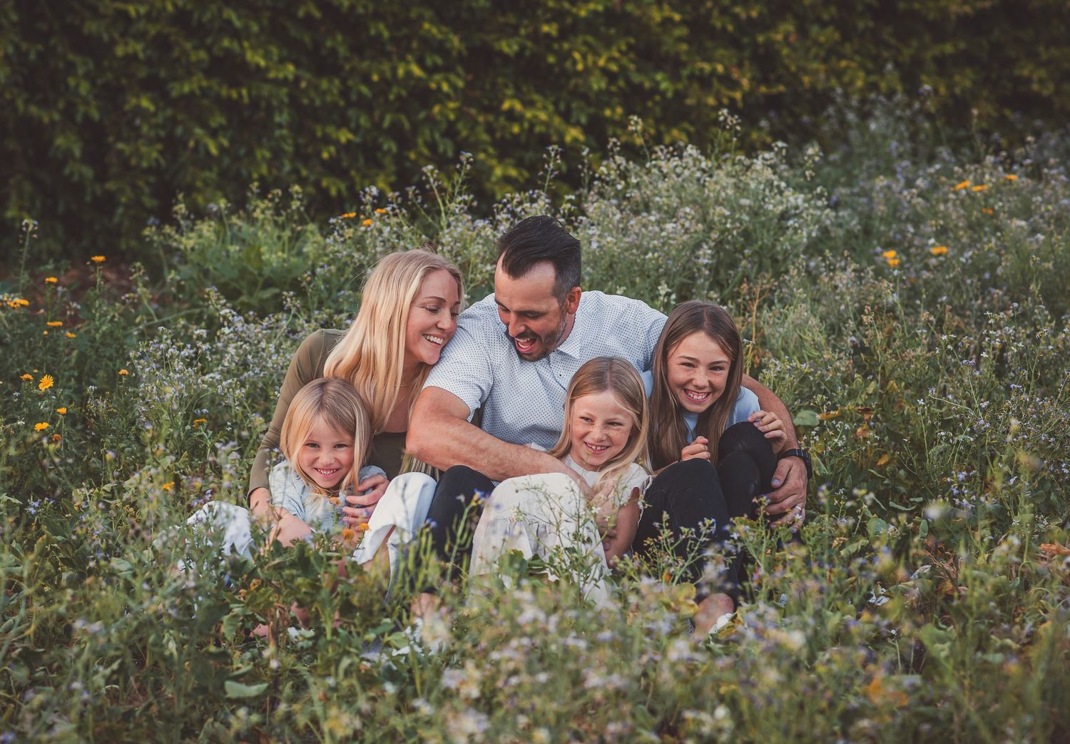 A family shares a candid moment together while sitting in a wildflower meadow.