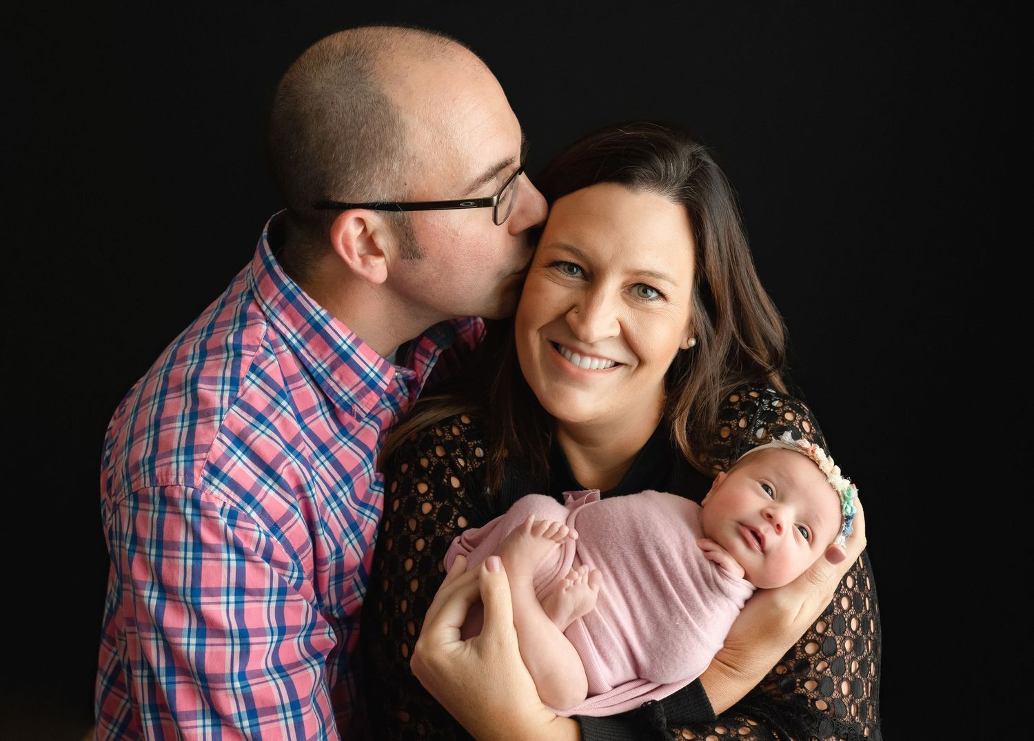 Dad is kissing his wife while holding their newborn.  Greenville SC newborn photographer, Easley, SC newborn photographer, Upstate SC newbor