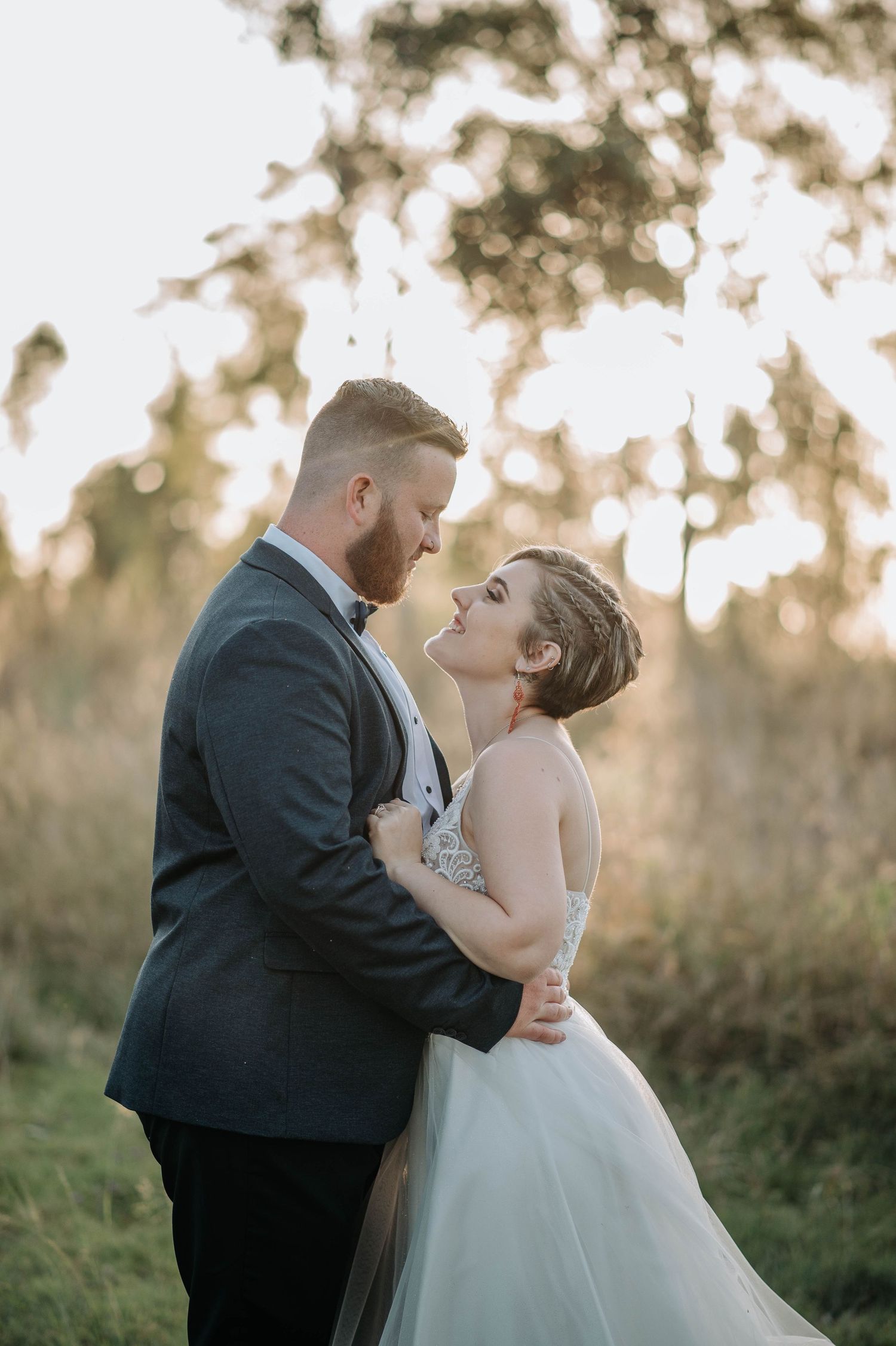 A romantic sunset wedding portrait with couple embracing in a meadow.