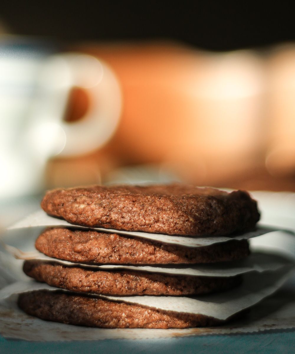 Stack of chocolate cookies with parchment paper between layers in soft focus.