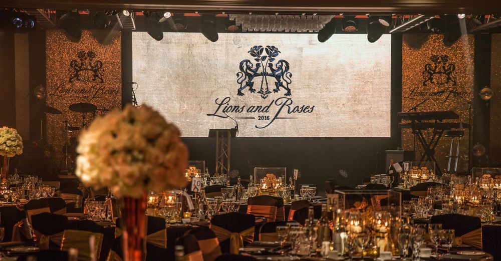 Elegant banquet hall setup with floral centerpieces and branded backdrop display.