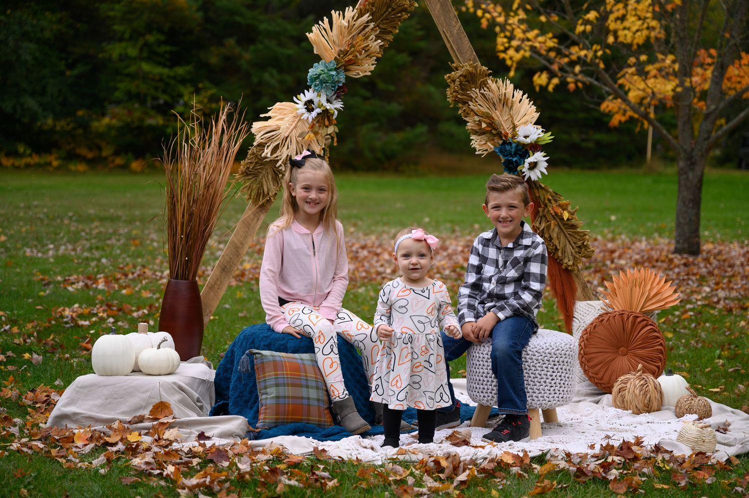 Three children pose on fall harvest scene in Orr, MN.