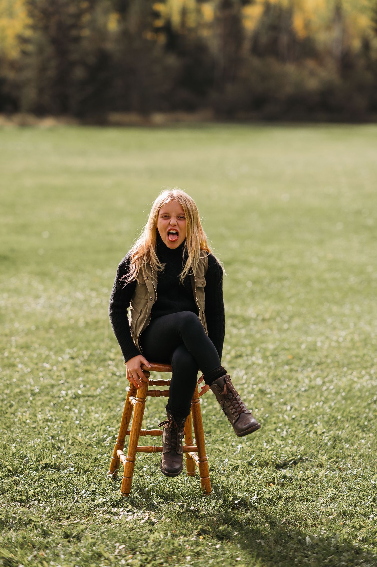 Young girl posing on chair in field in Orr, MN.
