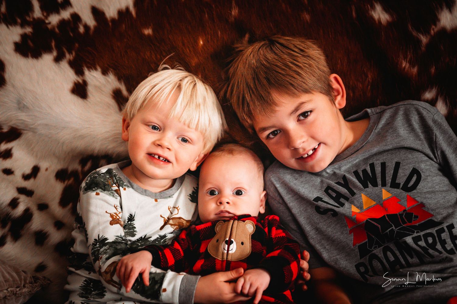 Three boys posing on cowhide background in Orr, Minnesota.