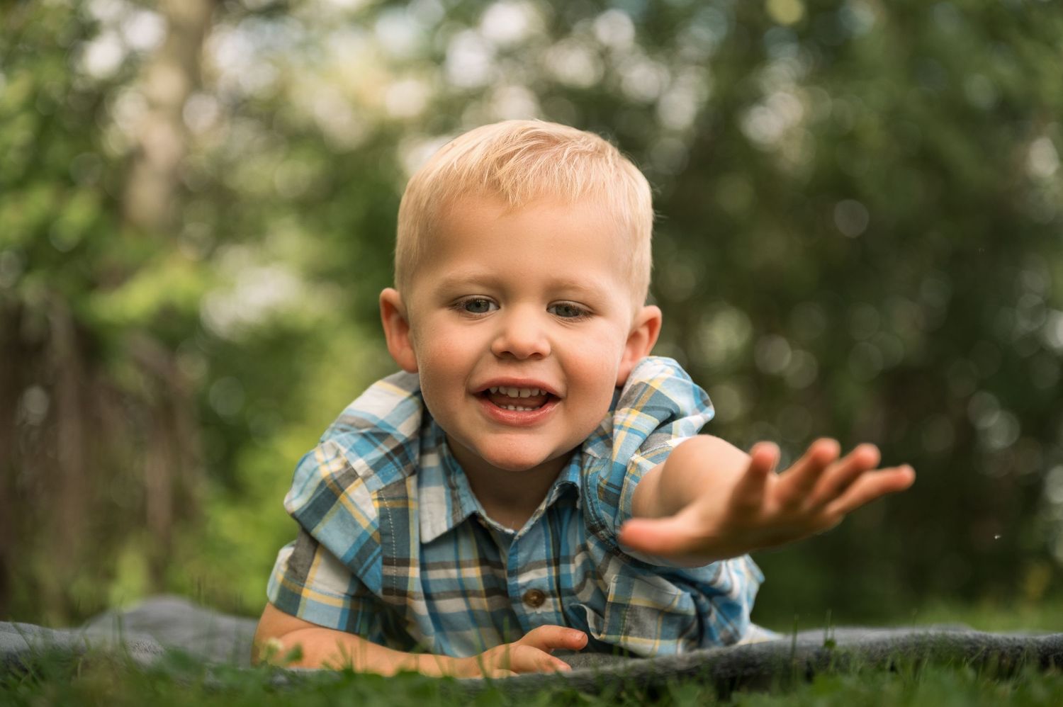 Young boy poses reaching out on summer background in Orr, Minnesota.