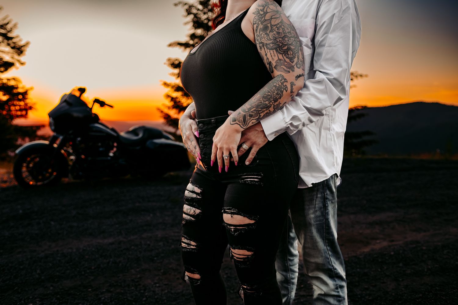 Couple posing at sunset with ripped jeans and casual attire in romantic setting.