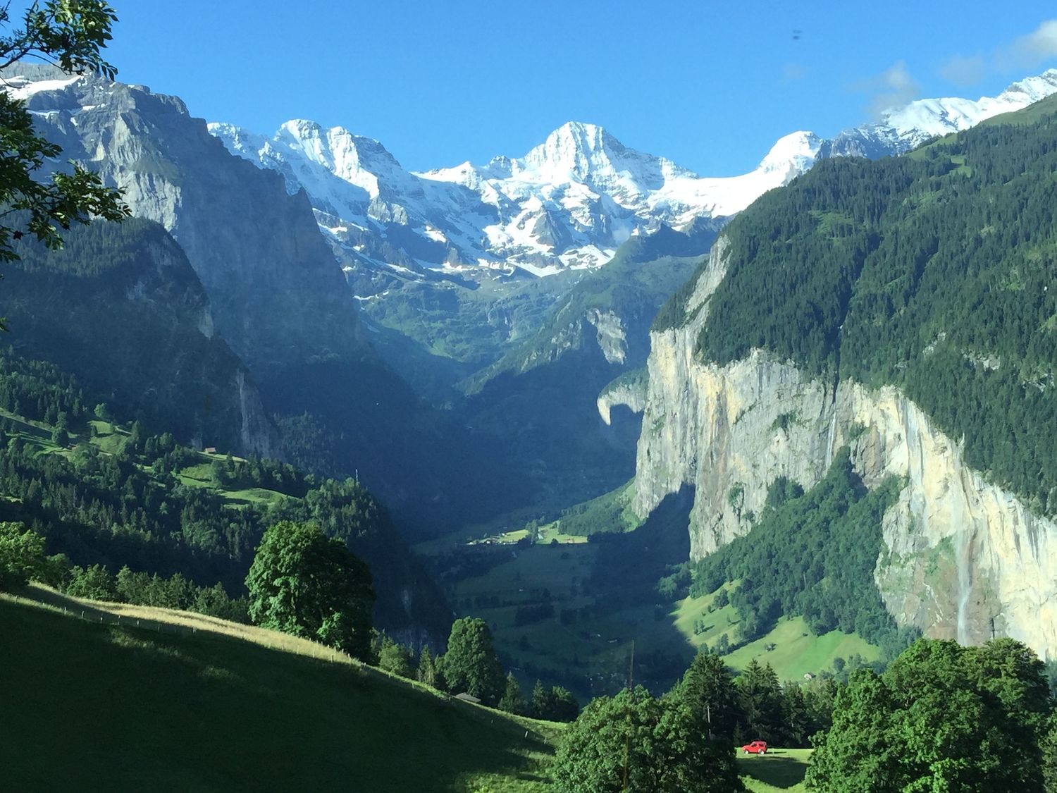 Scenic mountain valley landscape with snow-capped peaks and steep cliffs in Swiss Alps.