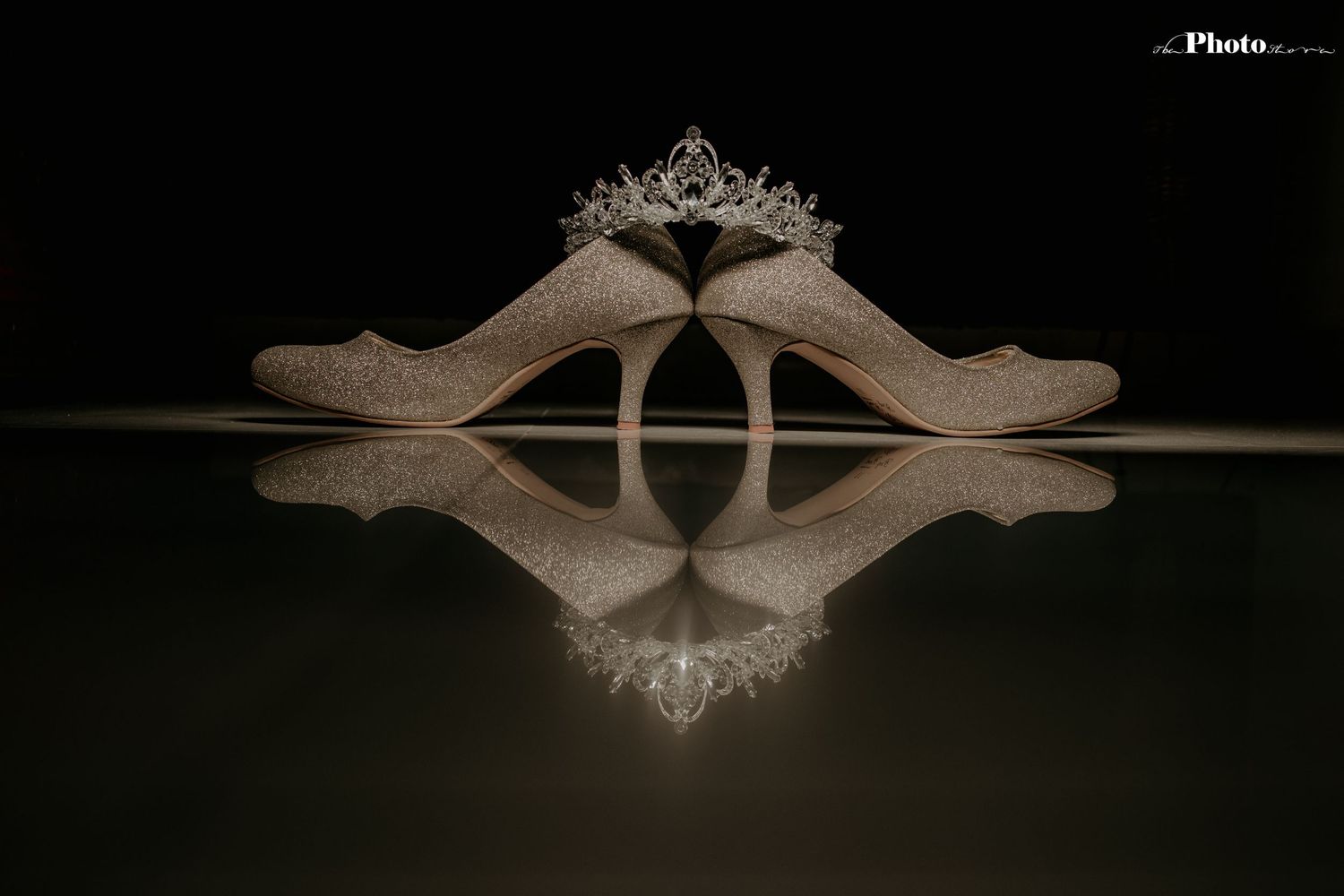 Ornate silver tiara displayed against dark background with mirror reflection.