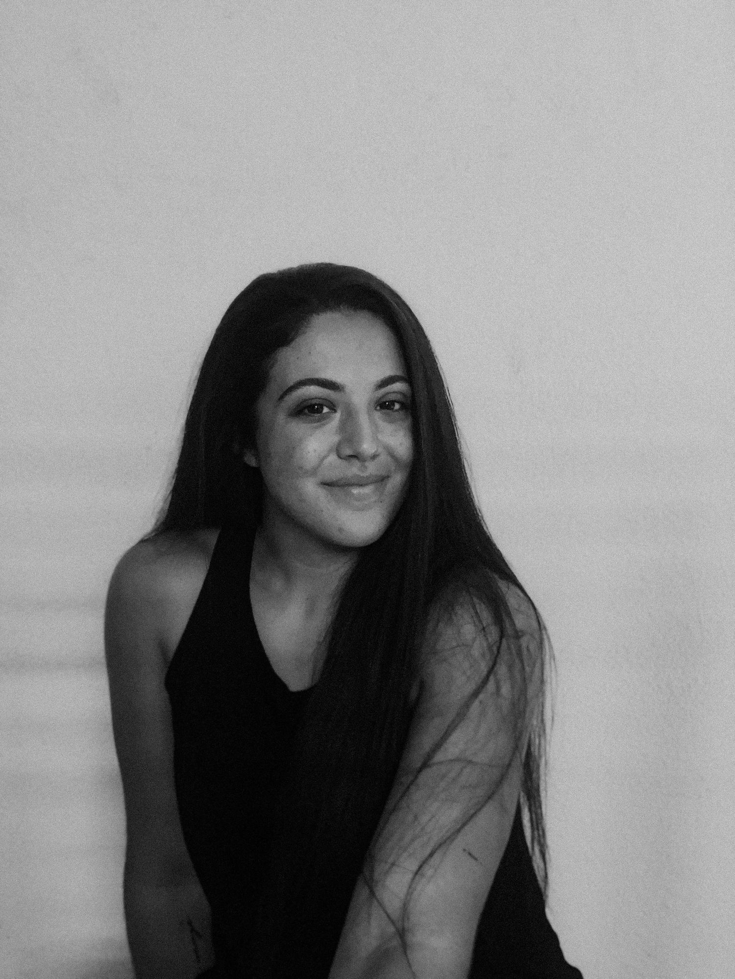 Black and white portrait of a woman in a dark sleeveless top with long dark hair.