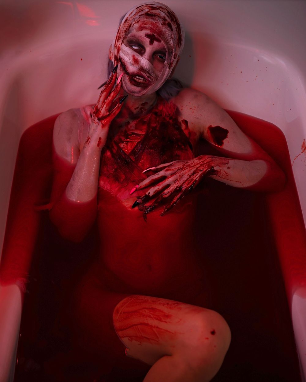 Dramatic red-tinted artistic photo of figure in bathtub with horror aesthetic.