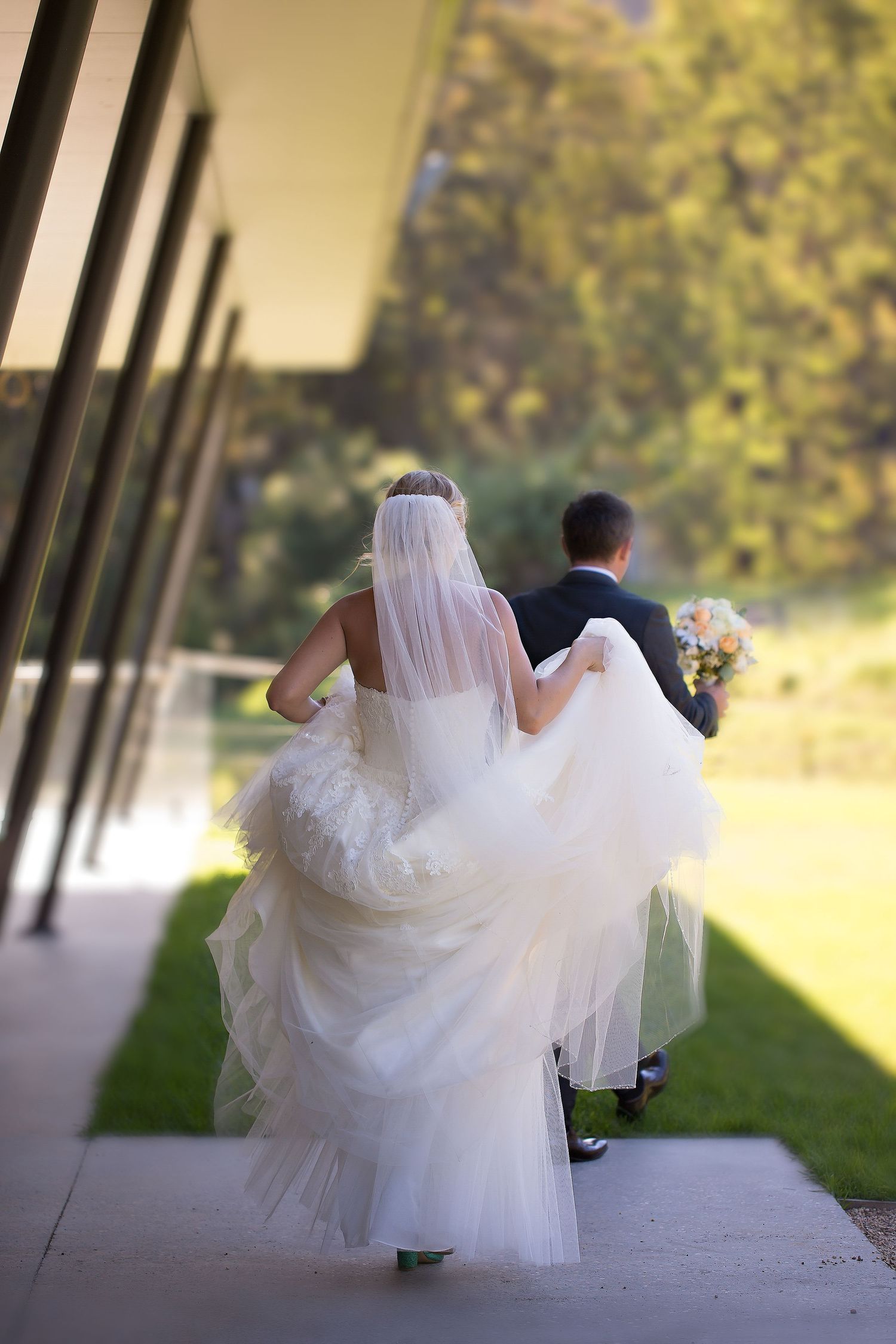 The groom holds his brides bouquet so she can hold her dress while they head back to their reception party.