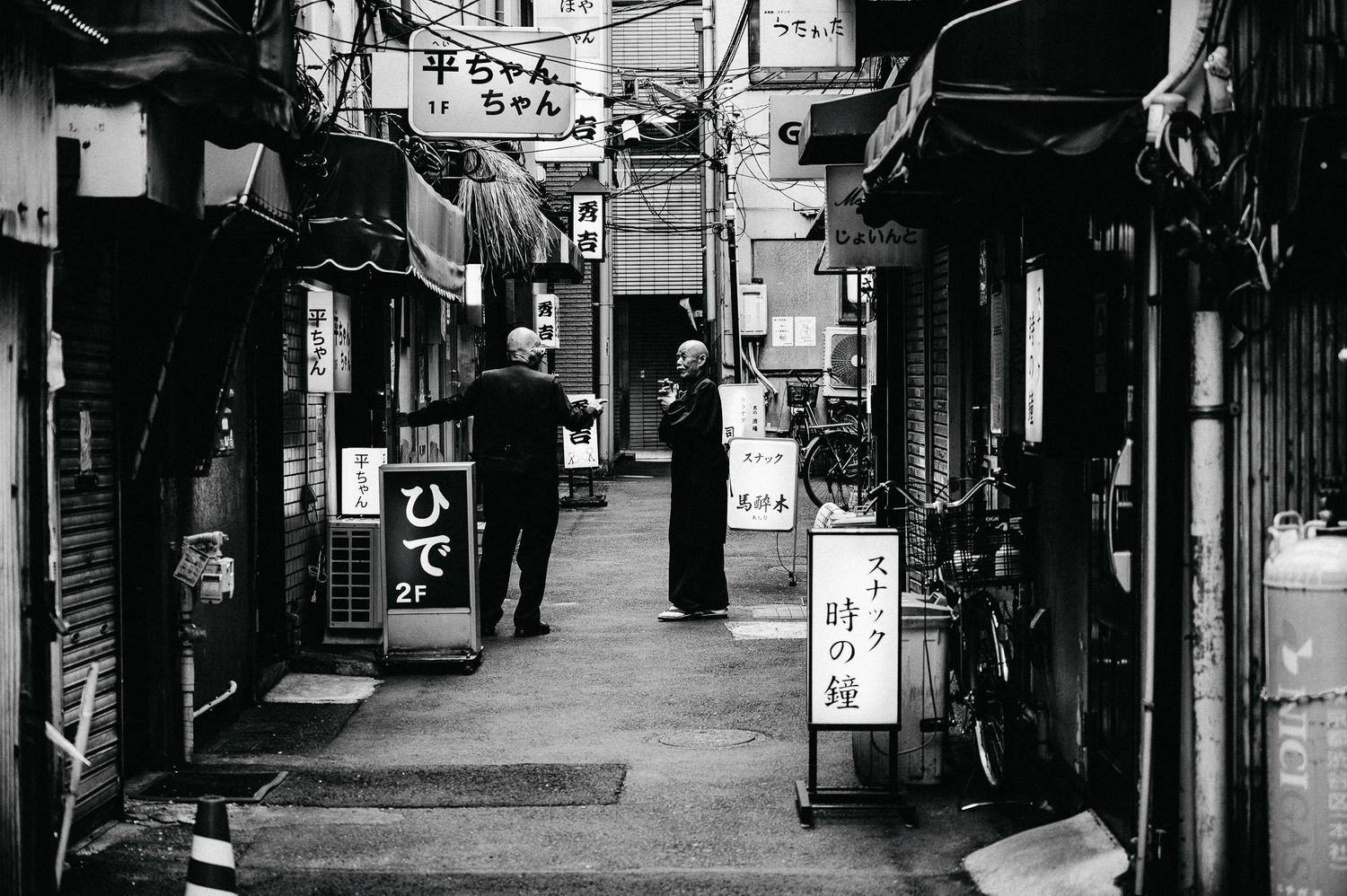 Black and white image of a narrow Japanese shopping alley with traditional signage.