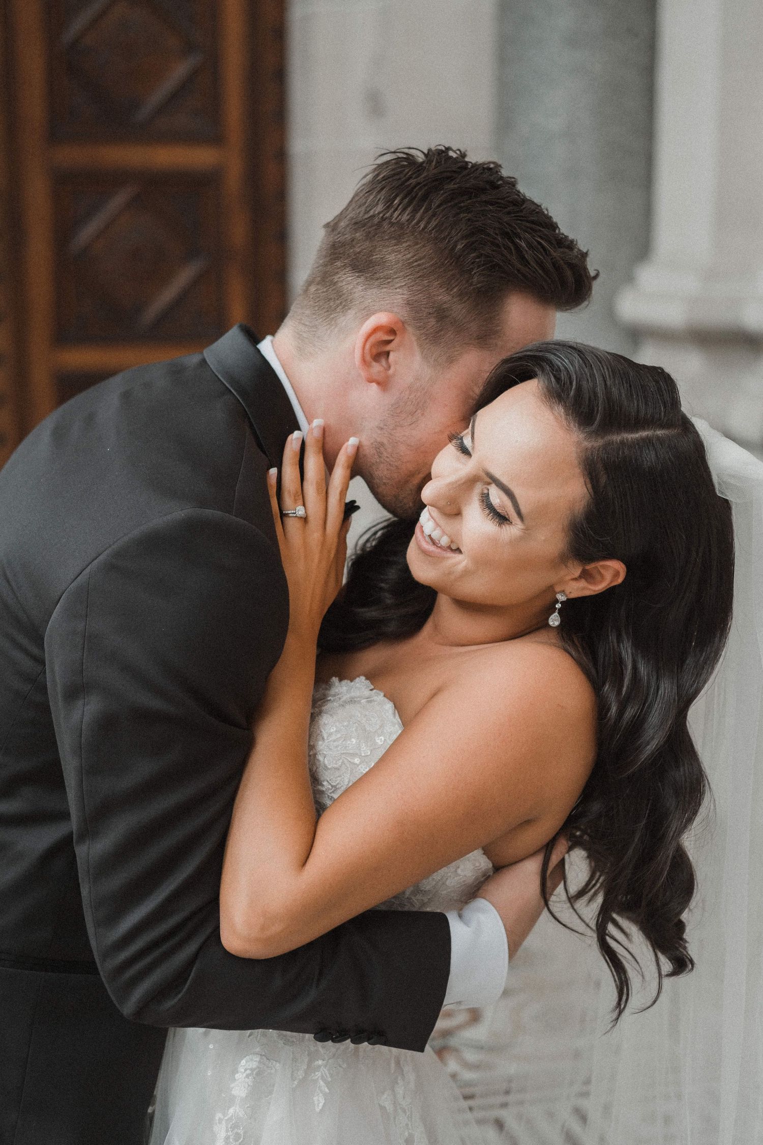 bride and groom embracing one another, laughing and smiling on wedding day
