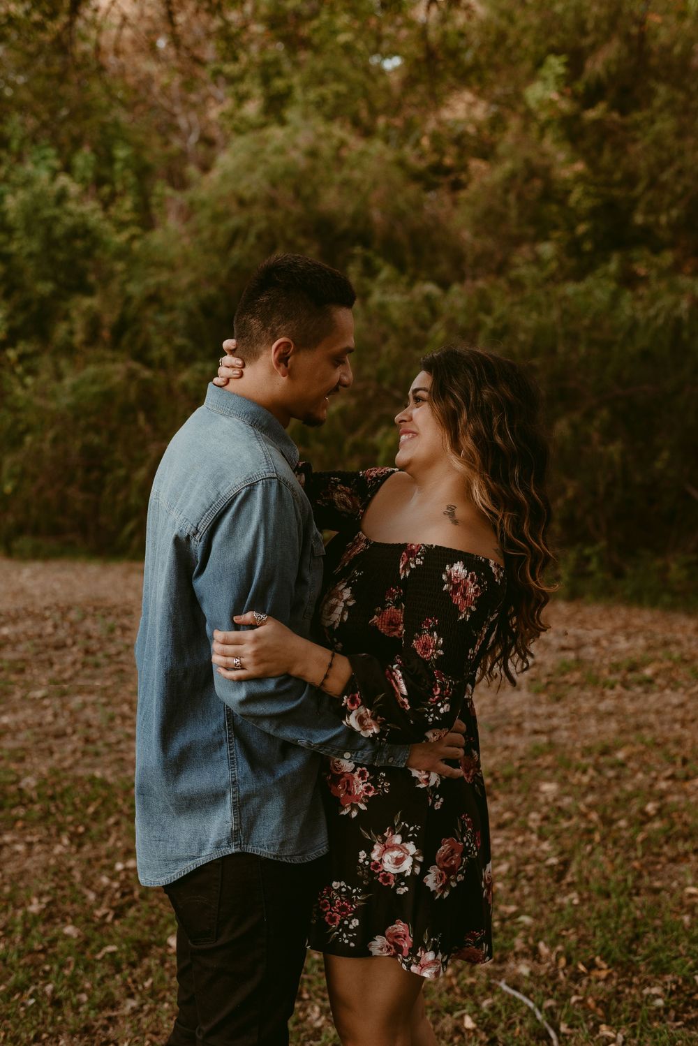 Romantic couple in casual attire sharing intimate moment in wooded setting.