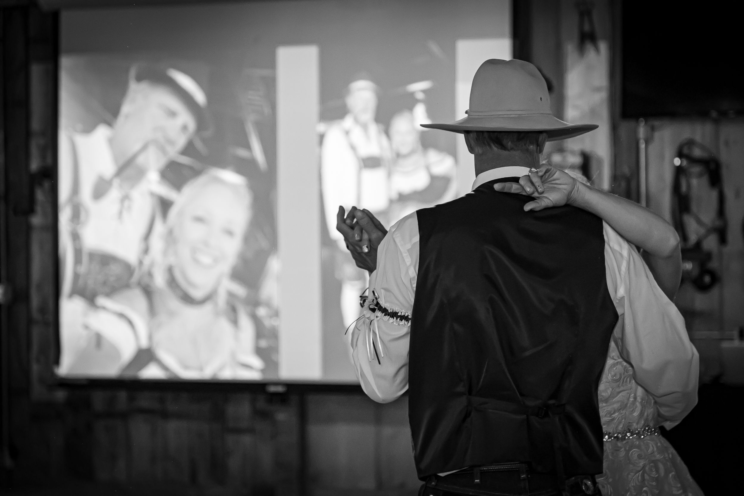 A silhouetted couple dances while vintage footage plays on a projection screen behind them.