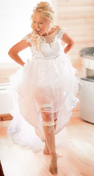 A joyful bride shows off her white lace wedding dress with delicate details.