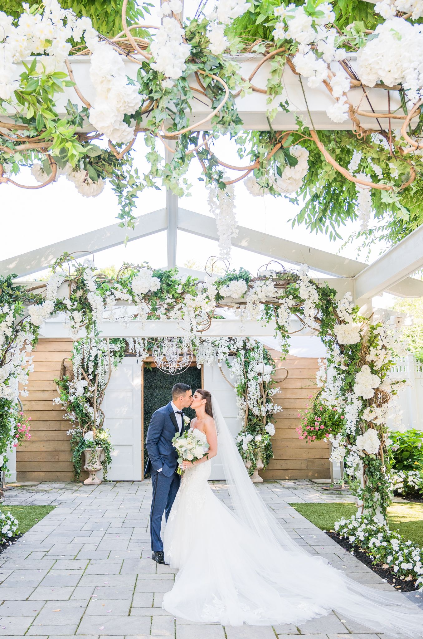 Couple kissing surrounded by flowers at their wedding.