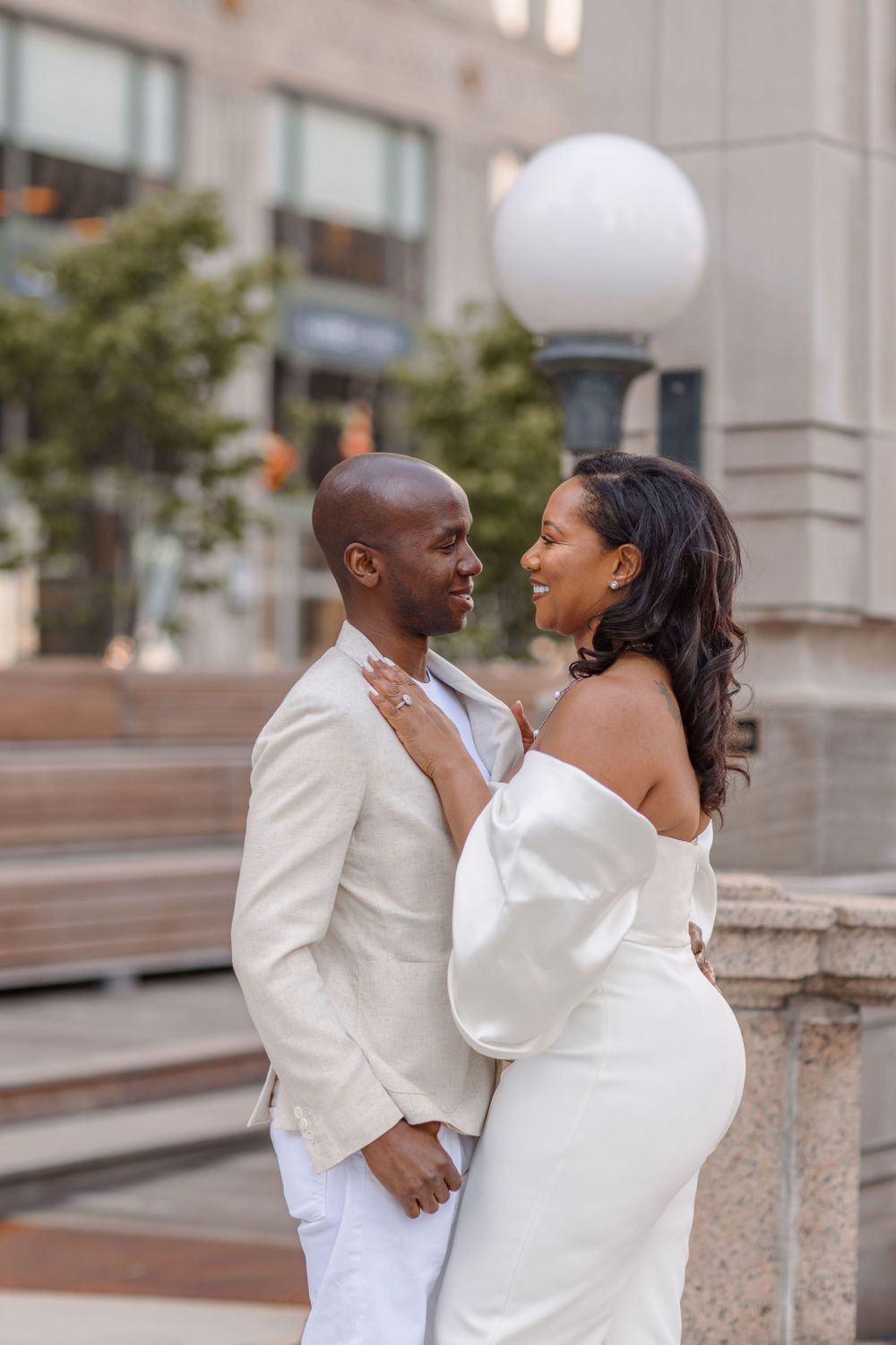 Romantic urban engagement photo of a couple in matching white outfits.