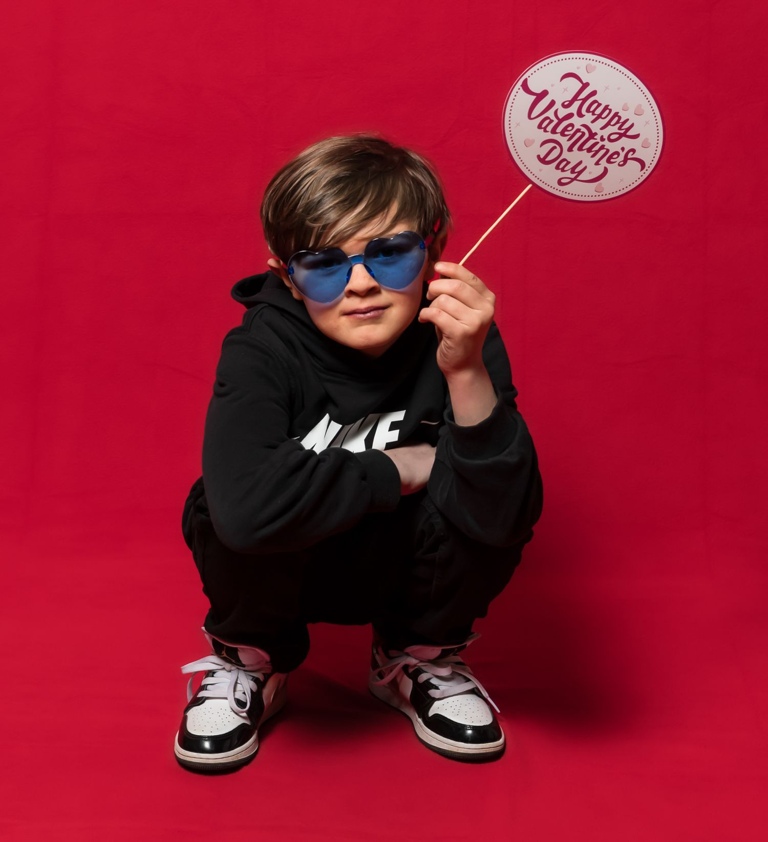 Playful fashion poses of a child in Nike wear against a bright red background.
