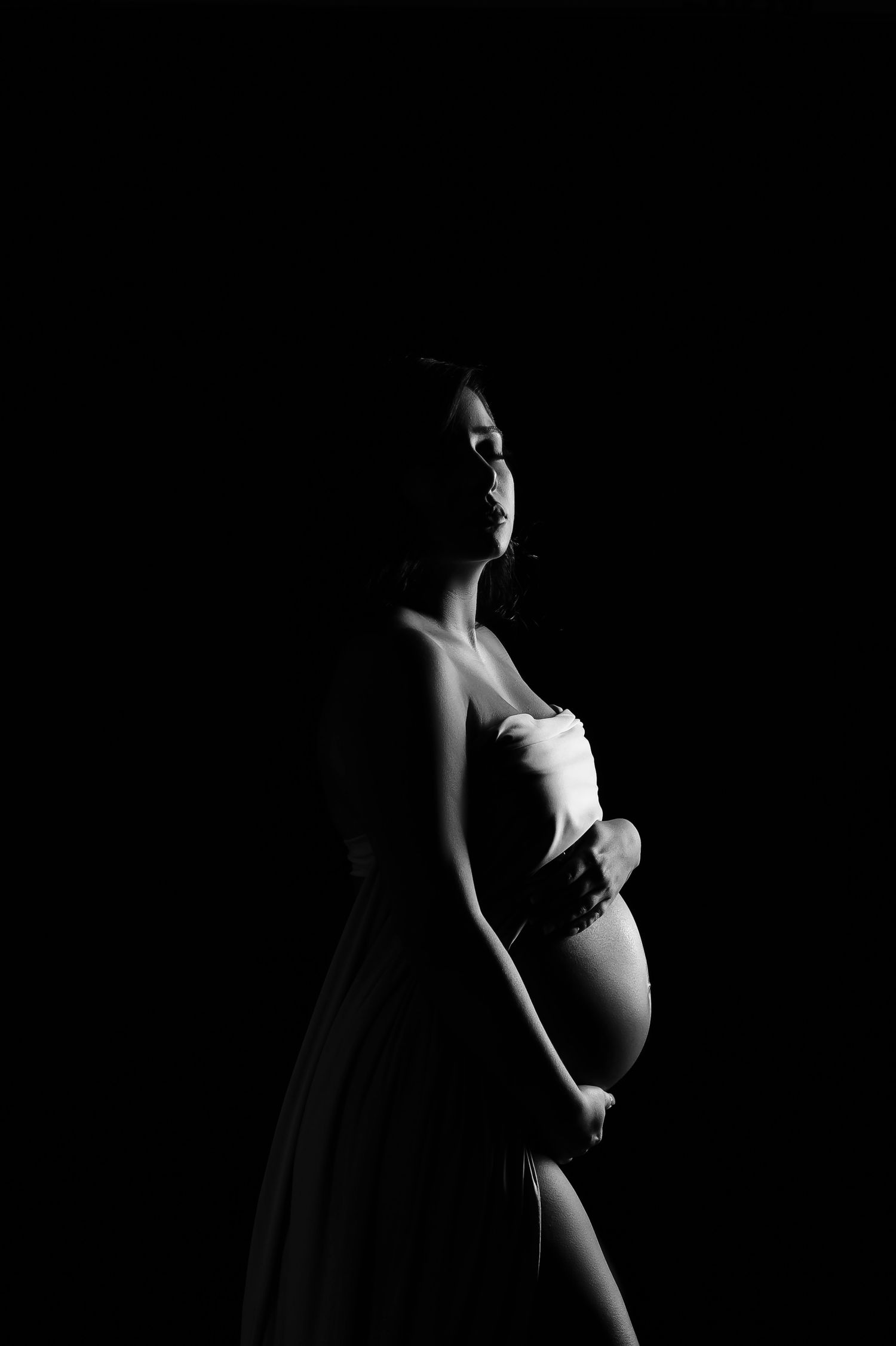 Black and white maternity portraits highlighting dramatic lighting and shadow play.