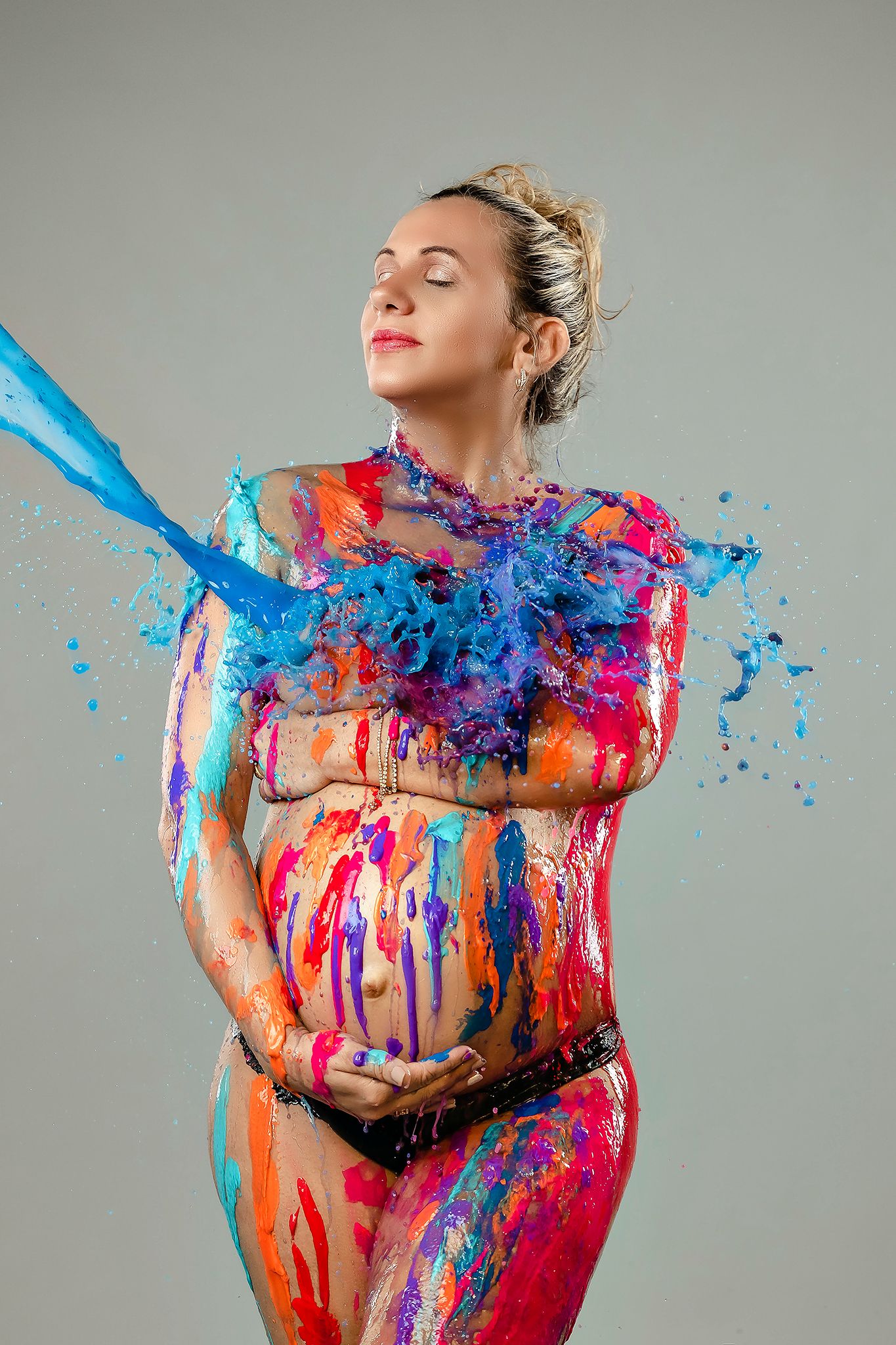 Dynamic portrait with splashing blue and pink paint creating artistic motion effect.