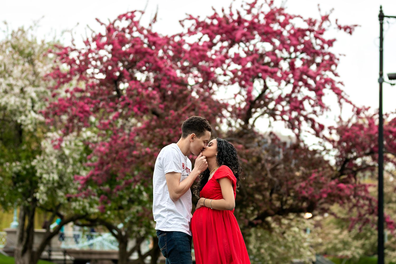Romantic couple embracing under blooming cherry blossom trees.