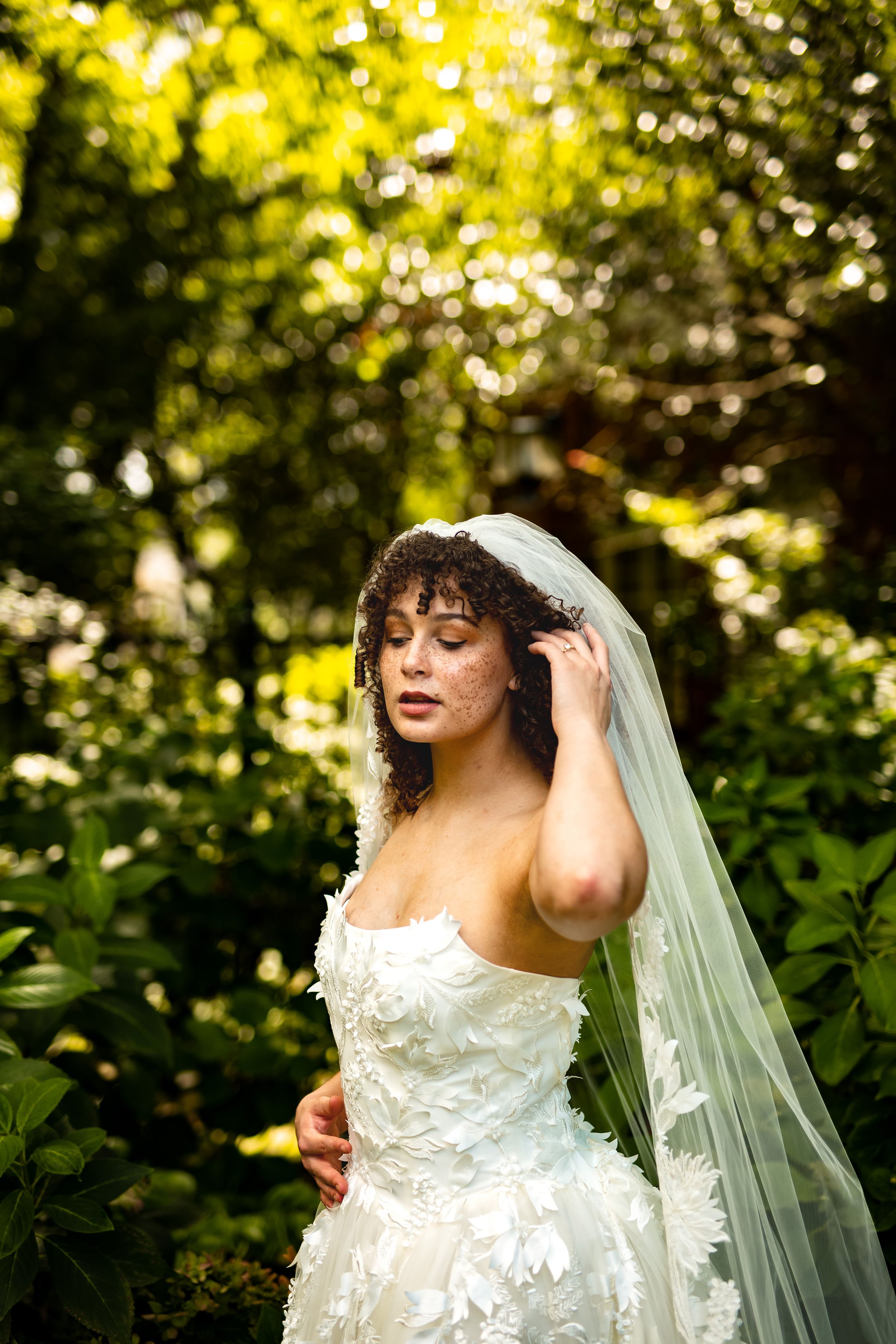 Artistic bridal portraits captured against lush greenery with natural sunlight filtering through trees.
