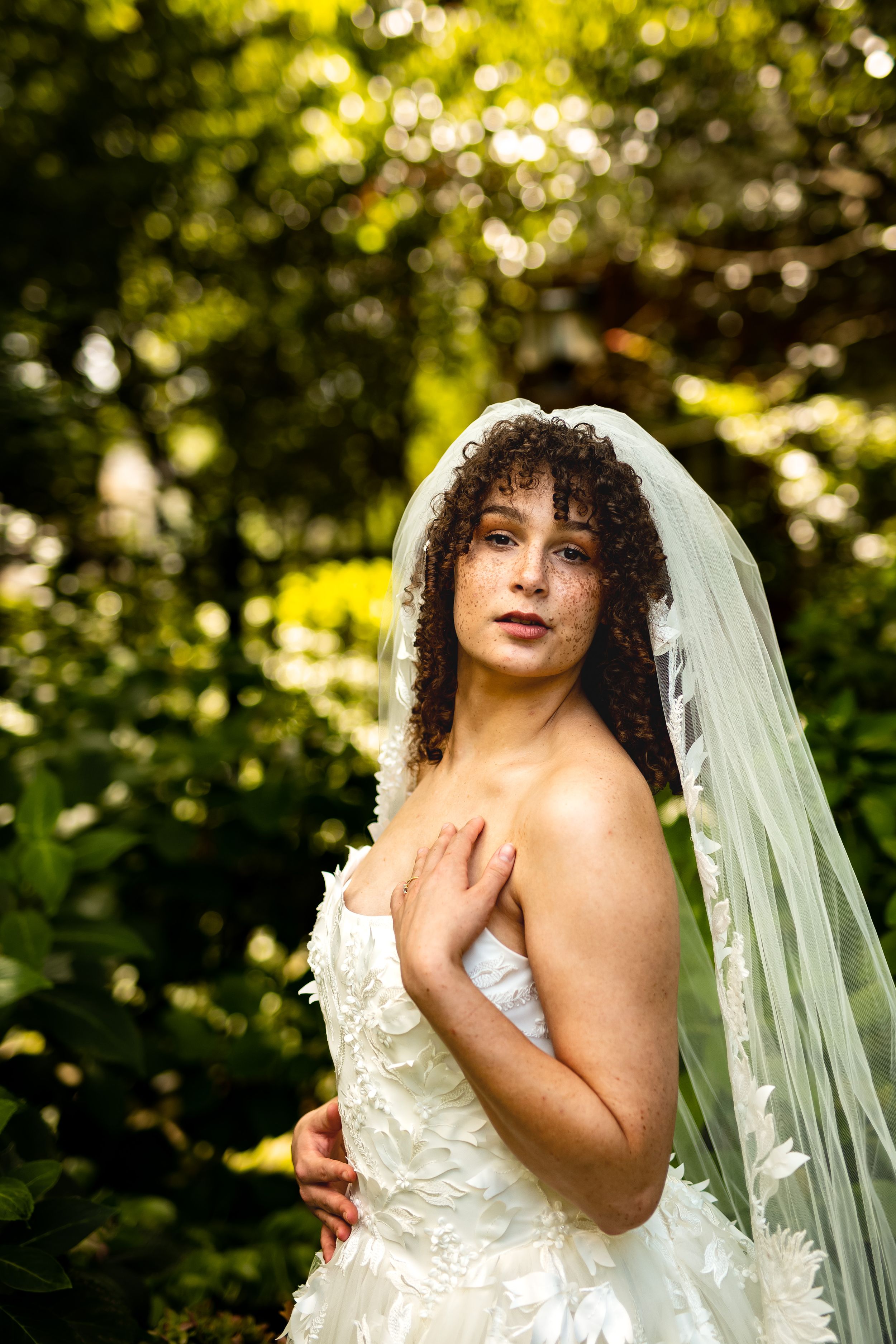 Ethereal bridal photography in a golden-lit outdoor setting featuring a strapless lace wedding dress.