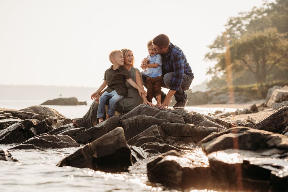A family sits on the rugged coast of Maine at golden hour.