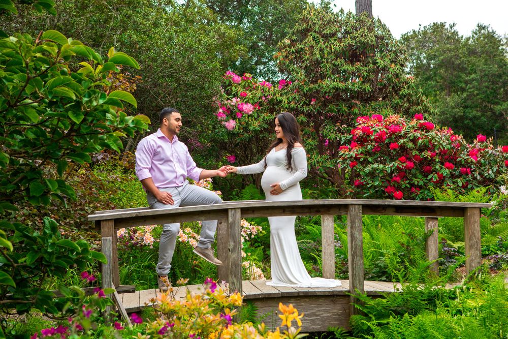 A romantic moment on a garden bridge surrounded by blooming flowers and greenery.