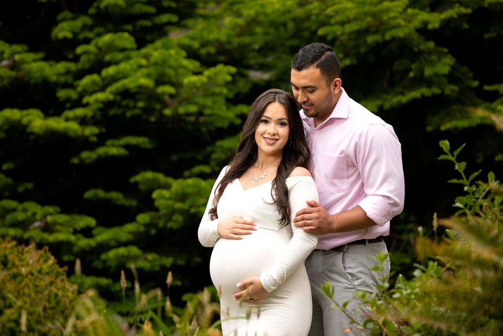 A maternity photo captured in a serene garden setting with soft natural lighting.