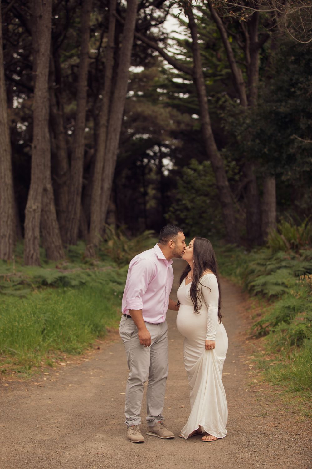 A tender moment captured on a forest path surrounded by tall trees.