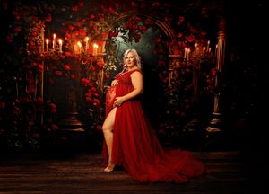 New Hampshire maternity photography of a pregnant woman in a red gown, fine art studio portrait with candlelit arches and romantic gothic