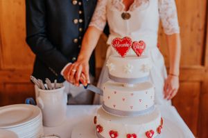 Hochzeitstorte verziert mit roten Herzen und Liebesverzierungen.