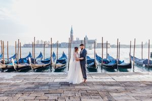 Hochzeitsfoto in Venedig mit traditionellen Gondeln und San Giorgio Maggiore im Hintergrund.