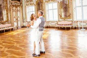 Eleganter Tanz in verziertem Goldballsaal mit klassischer Architektur. Hochzeitspaar
