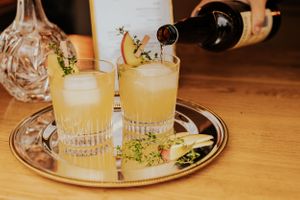 Zwei Zitruscocktails, garniert mit Kräutern, serviert auf einem Silbertablett.