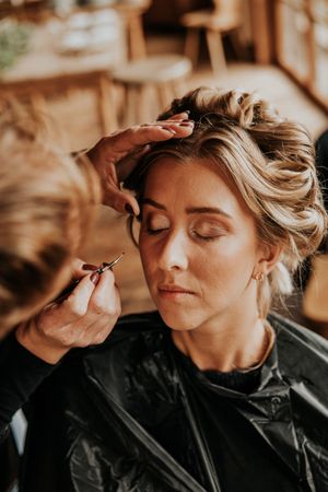 Nahaufnahme der Make-up-Anwendung am Hochzeitstag bei warmem Licht.
