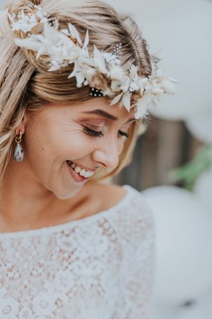 Zarte weiße Blumenkrone, die blondes Haar im Brautporträt schmückt.