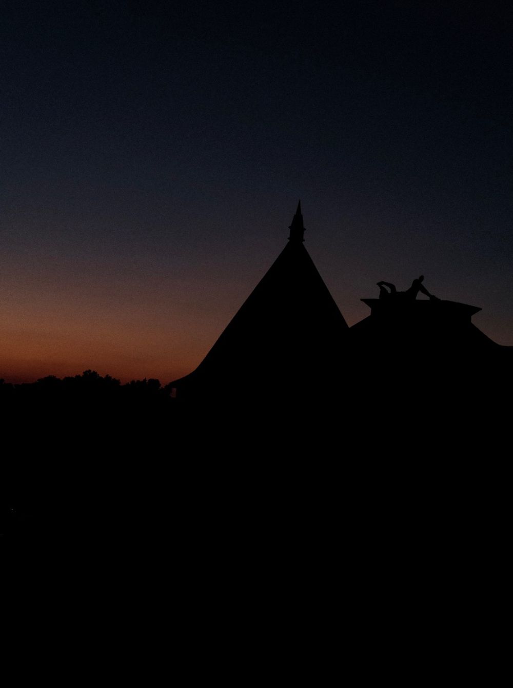 boy relaxing on the top of a church at sunset