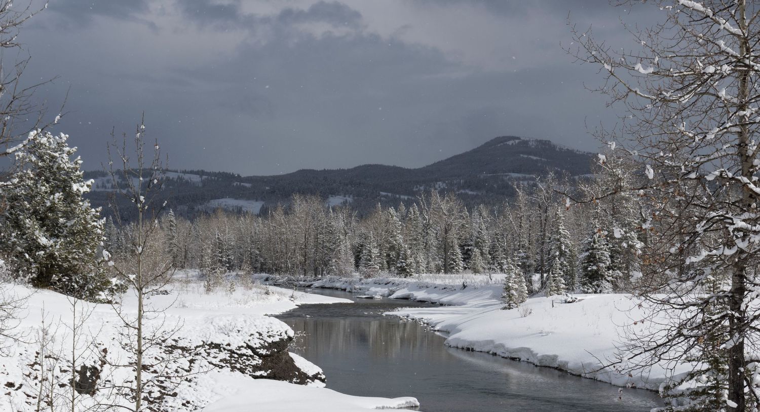 Snow-covered winter landscape with winding river through mountainous terrain.