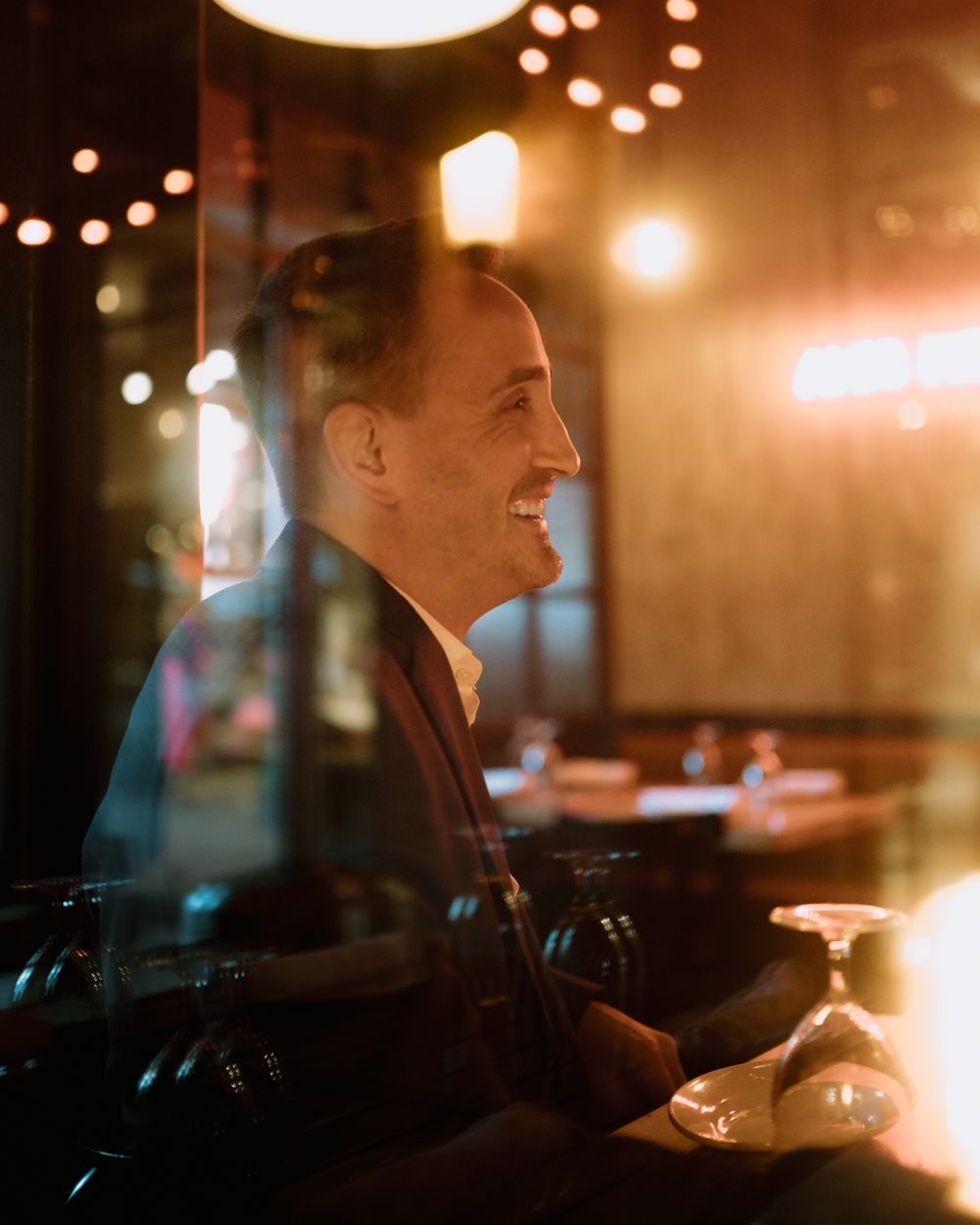 A profile view of someone enjoying a drink in a romantically lit restaurant setting.