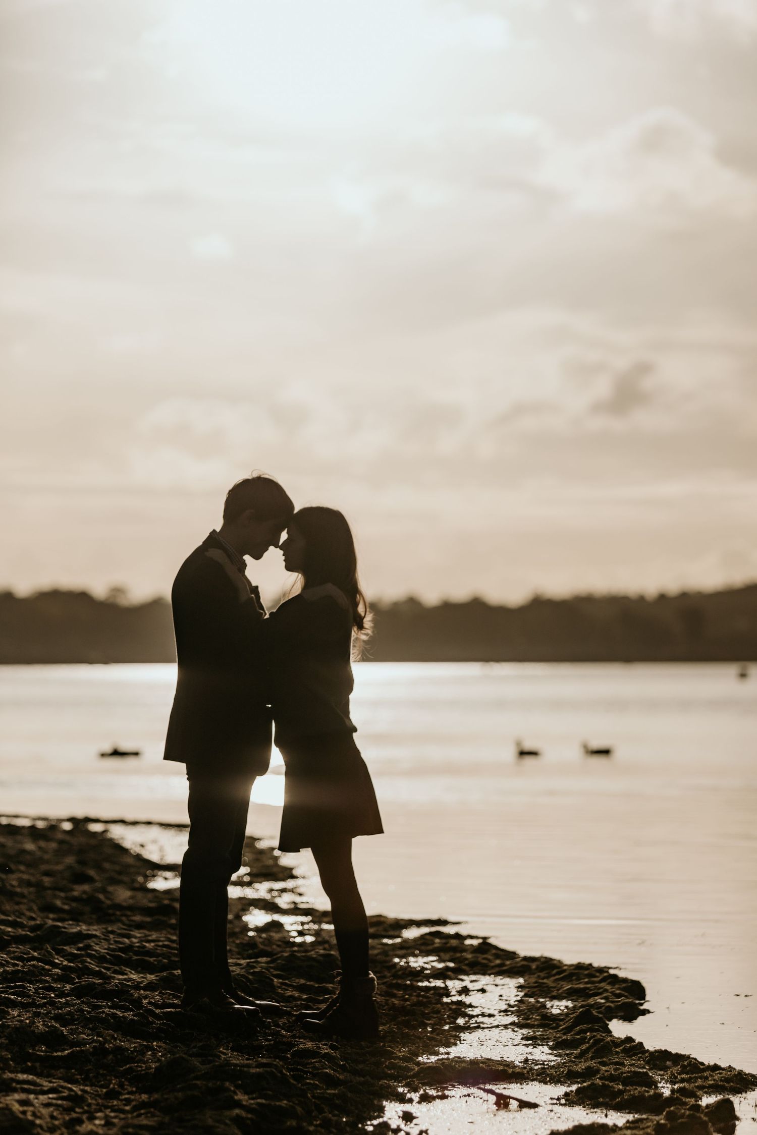 couple stood next to rutland water at sunset