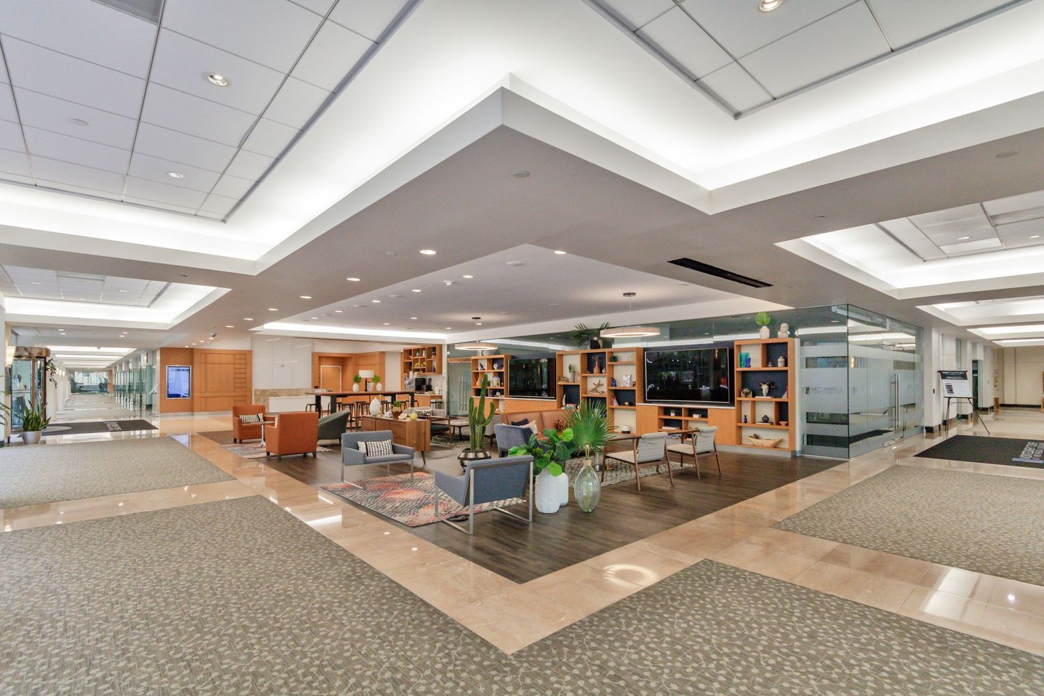 Modern office lobby with contemporary furniture, warm lighting, and geometric ceiling design.
