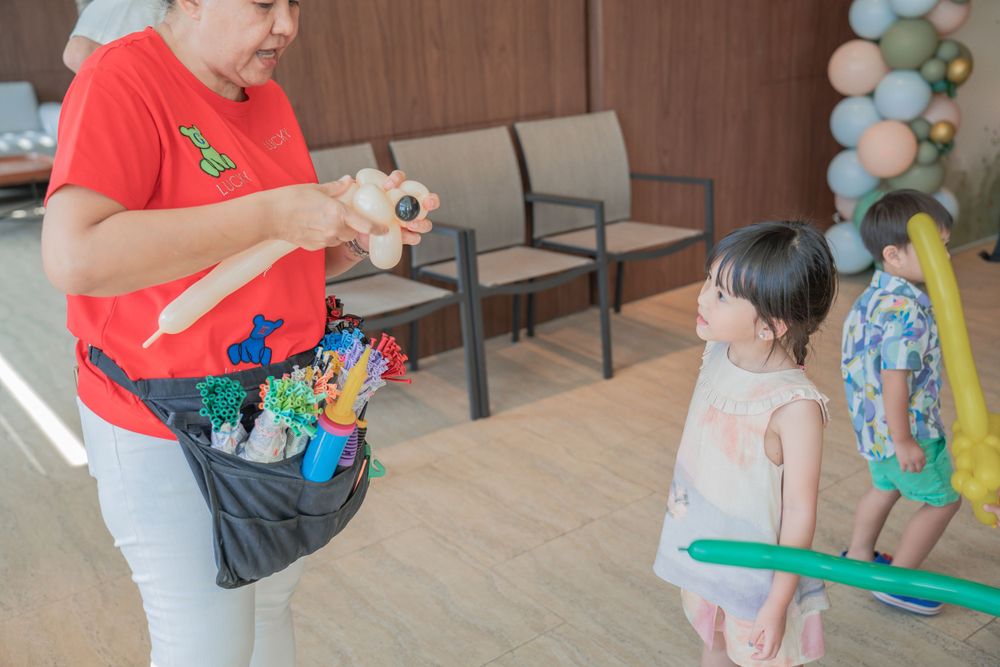 Party entertainer creating balloon animals for young guests at an indoor celebration.