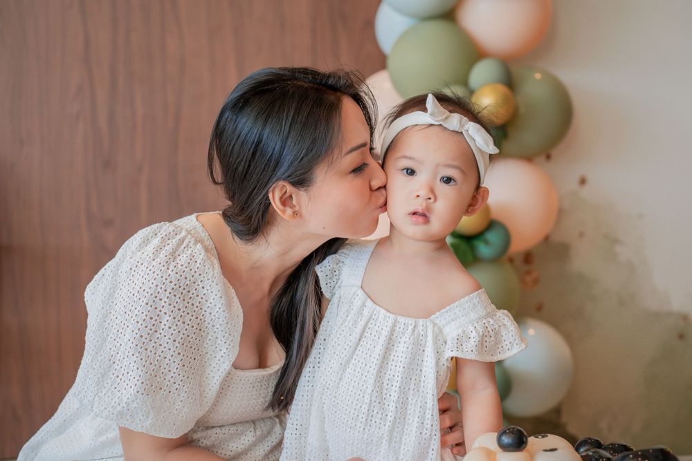 Matching white dresses at a birthday celebration with pastel balloon decorations.