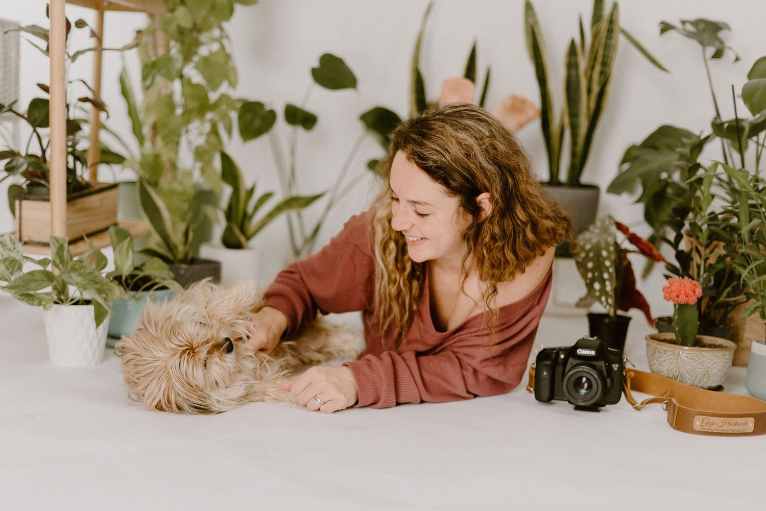 Gigi Hartwick petting her dog surrounded by her plants and camera for Shooting the Moon Photography.