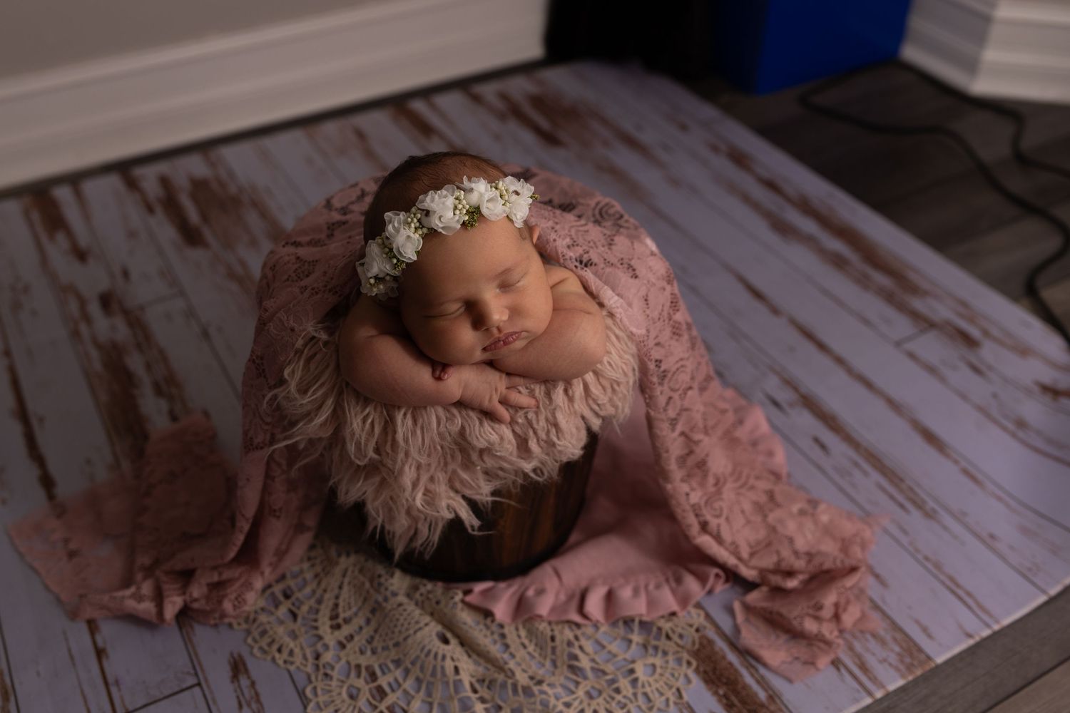 Newborn photography with baby sleeping on pink blanket with floral crown.