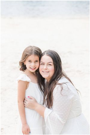 A heartwarming moment captured between two people in white outfits against a bright background.